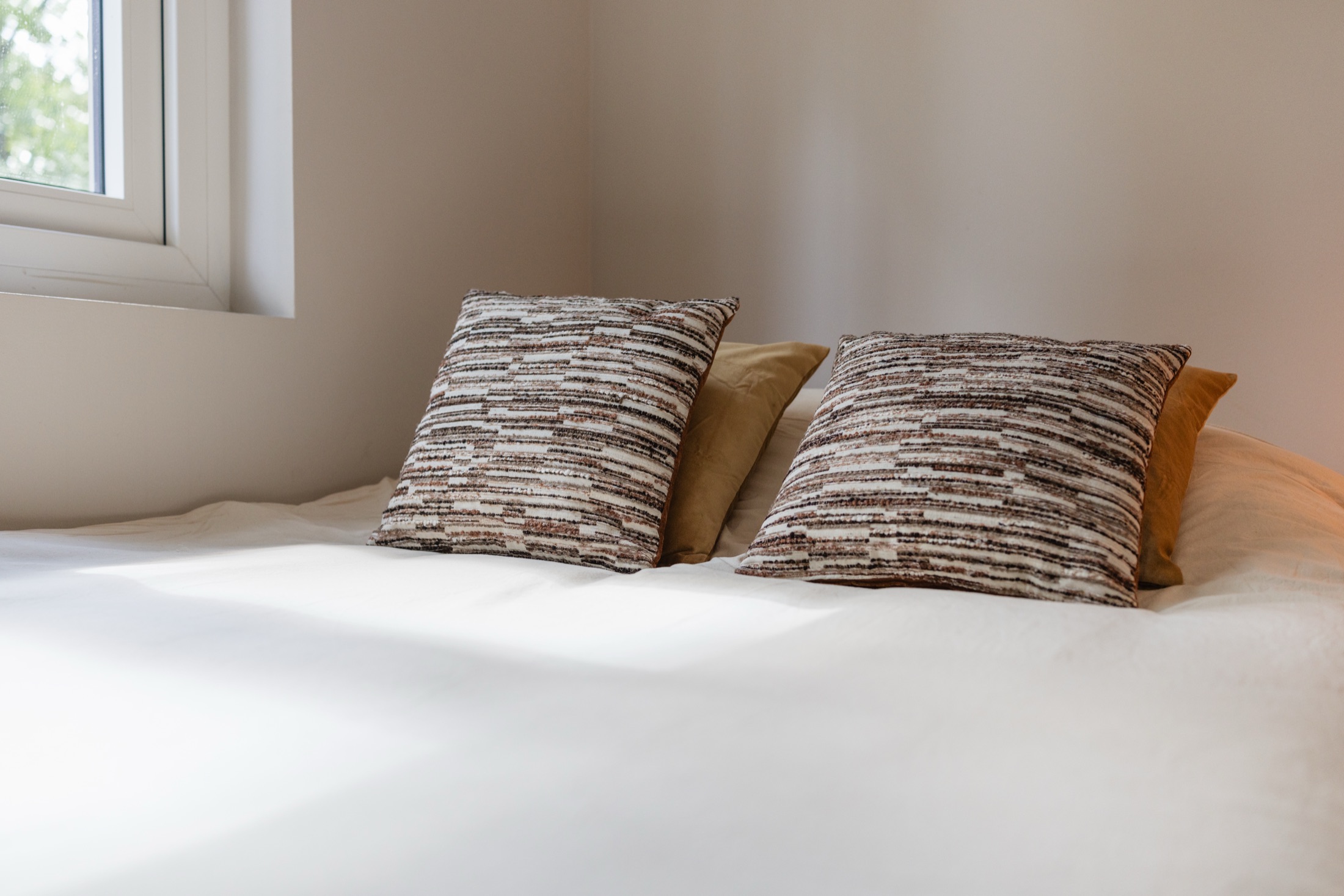 Kussens op het opgemaakte bed in ochtendlicht